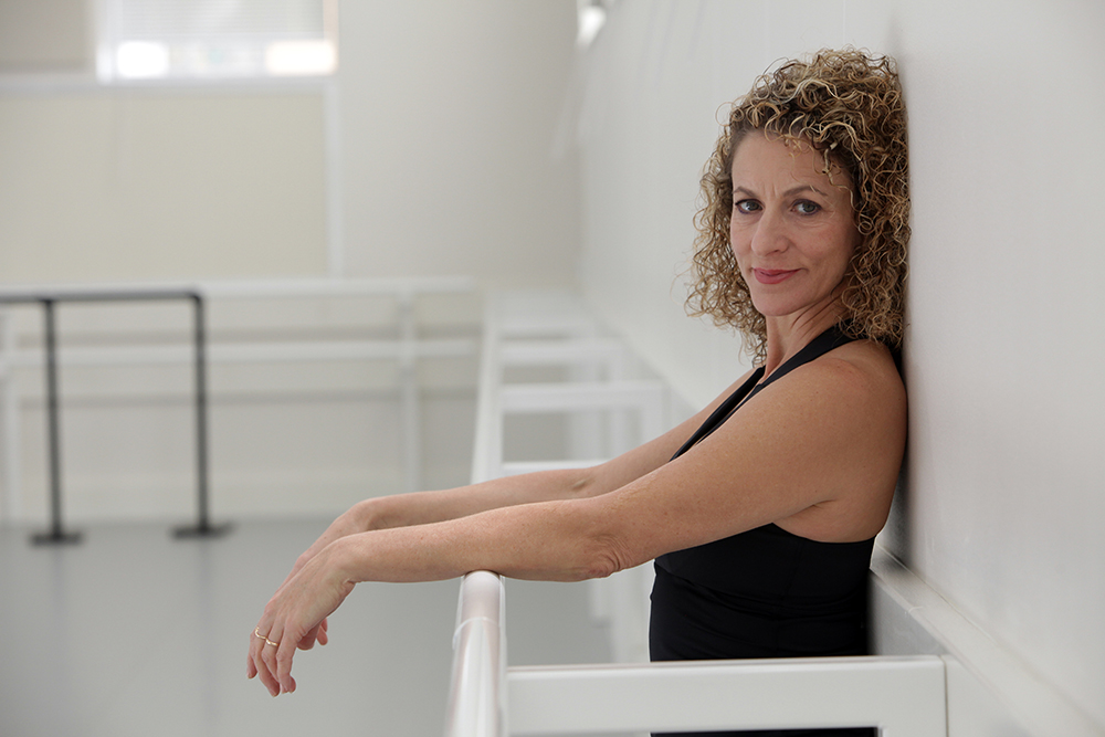 Suki John leans against the wall of a dance studio