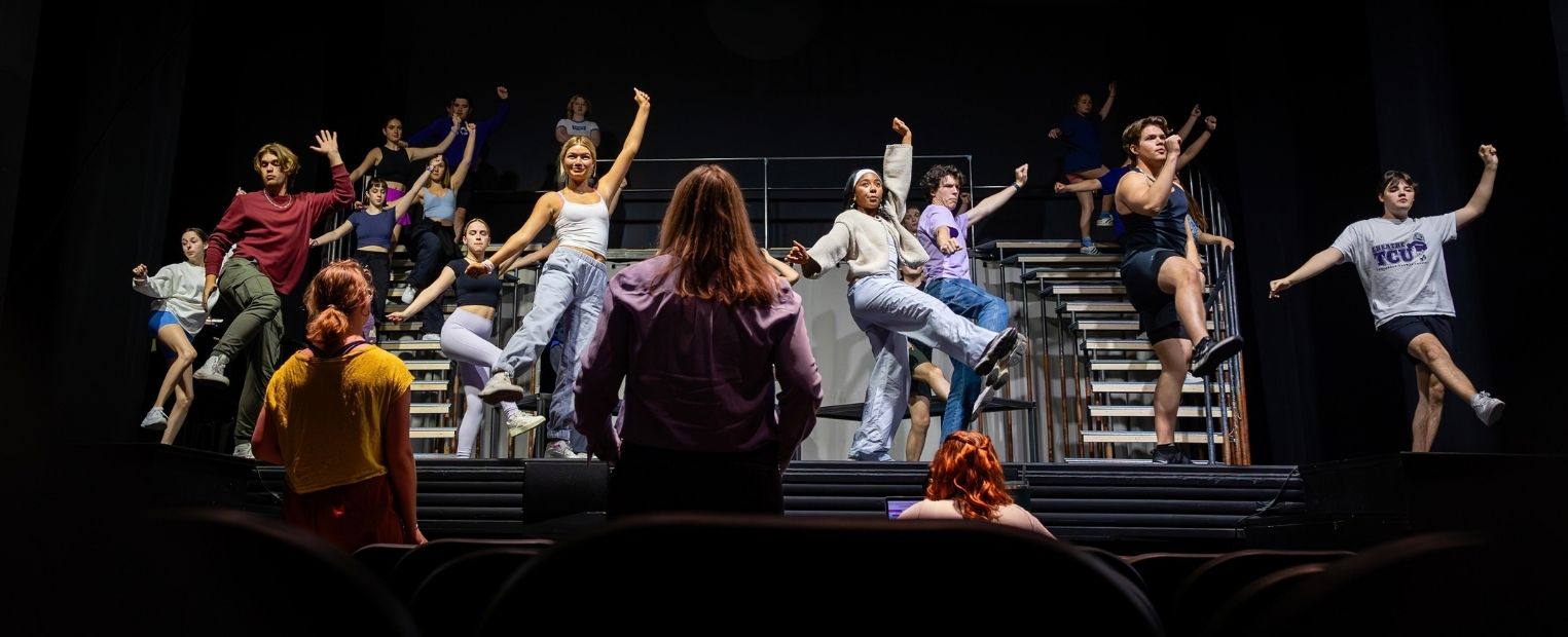TCU Theatre students rehearse a dance number onstage, performing choreography across a multilevel set.