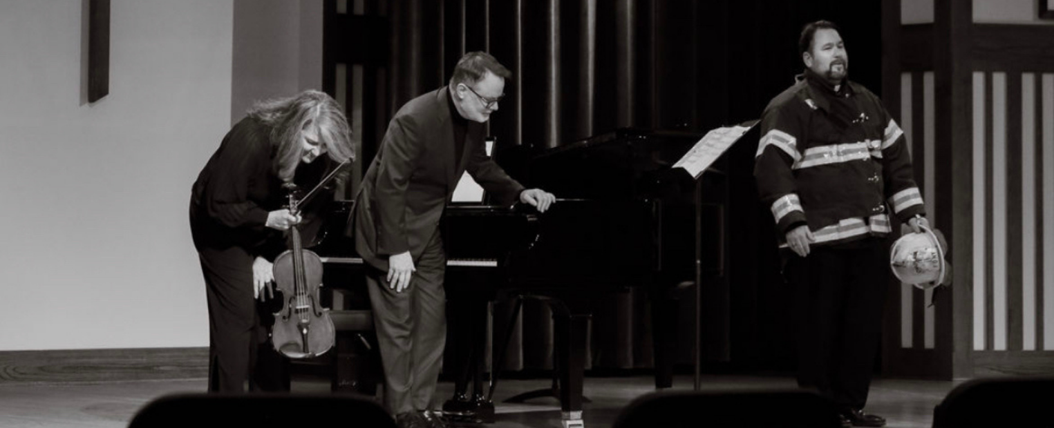 Black-and-white panorama showing the performers’ curtain call. Dr. Ames Asbell bows with viola in hand, Dr. Joey Martin leans forward beside the piano, and Dr. Richard Novak, now wearing a fire fighter suit.