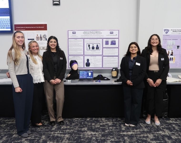 TCU student researchers stand beside their wearable technology prototypes and research posters at the Texas Space Grant Consortium workshop.