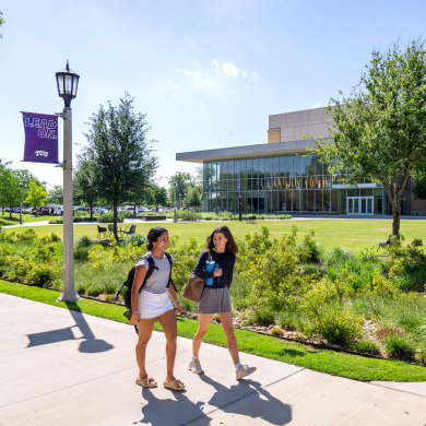 Two students walking in front of the TCU Music Center building