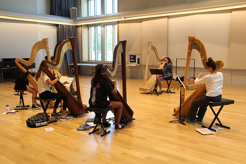 A group of summer campers play harps in the studio