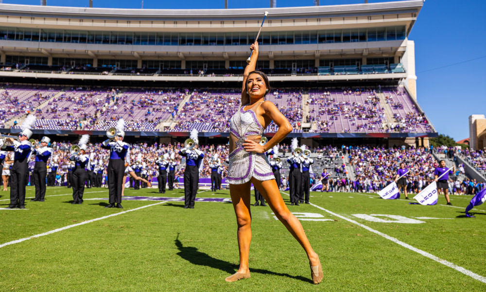 twirler on football field with band