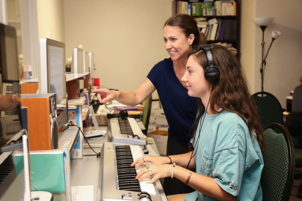 Teacher helping student in the Music Prep computer lab