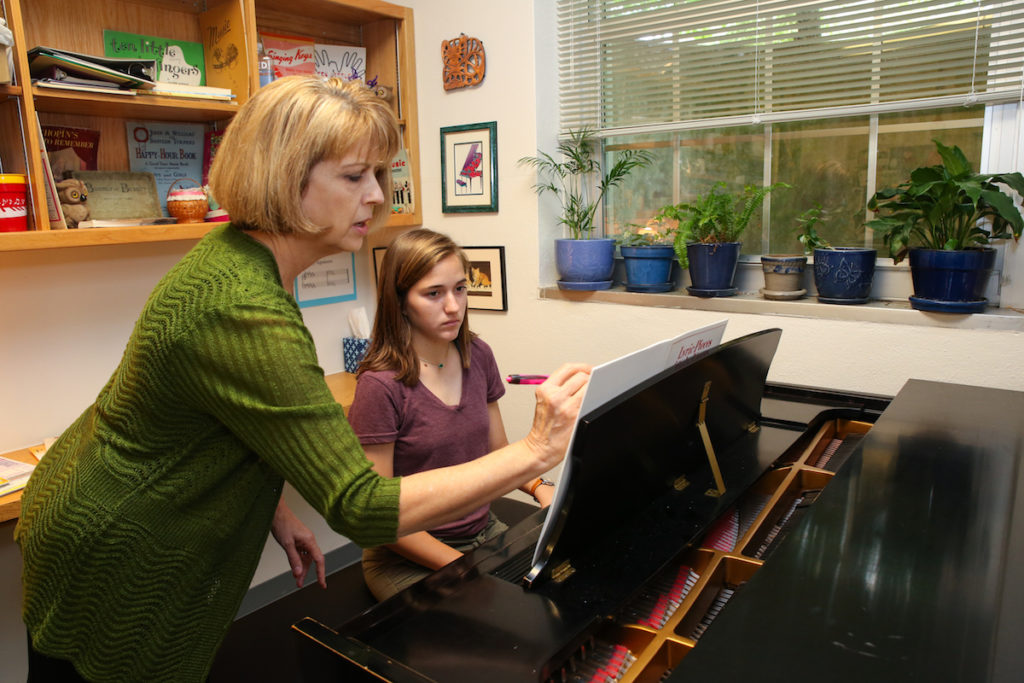 Piano teacher teaching student to play piano