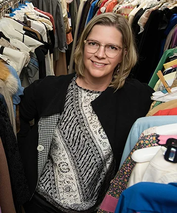 Stephanie Bailey stands between rows of brightly colored costumes