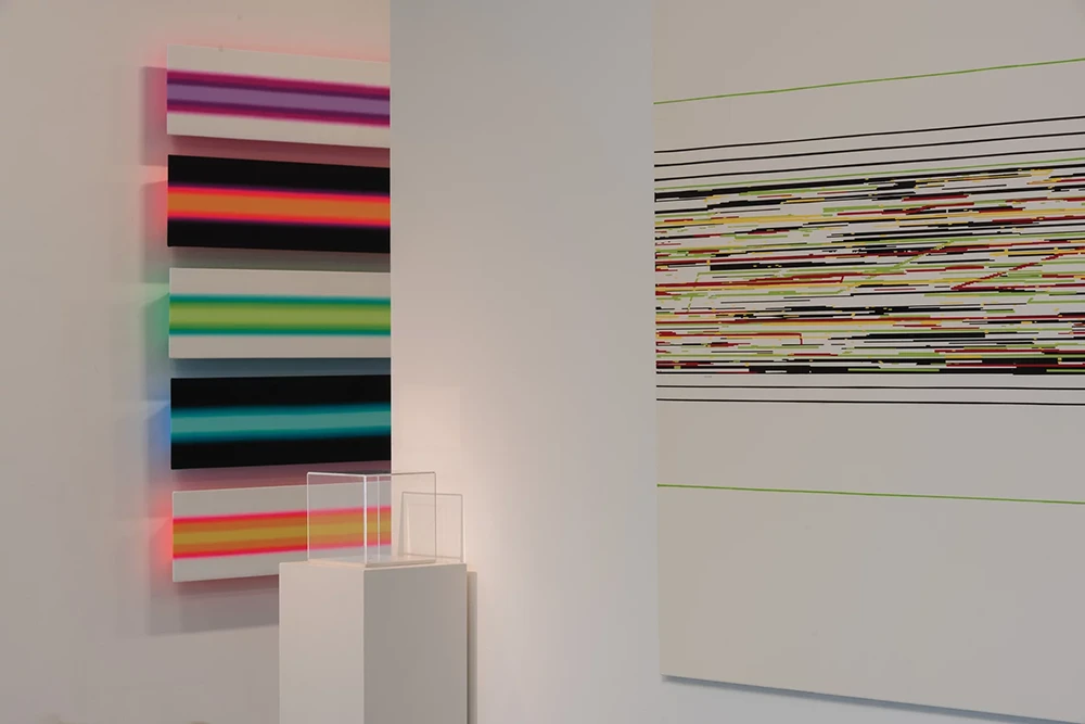 Two of Colpitt's pieces, one a series of backlit panels and one a painting of intricate, geometric line work