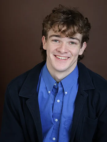 Henry Cawood, wearing a dark jacket and a bright blue shirt