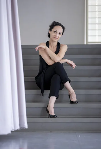 Jessica Zeller, seated on gray steps next to a light purple curtain