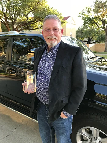 Michael Skinner stands holding an award in his right hand