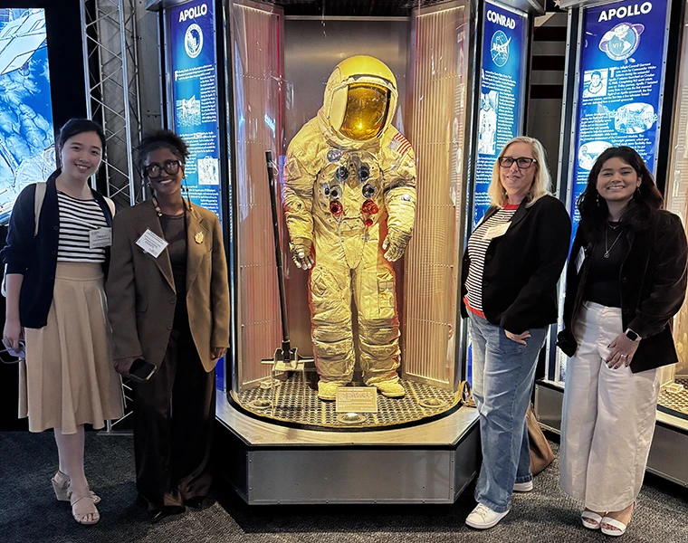 TCU Fashion Merchandising students stand next to a NASA spacesuit display