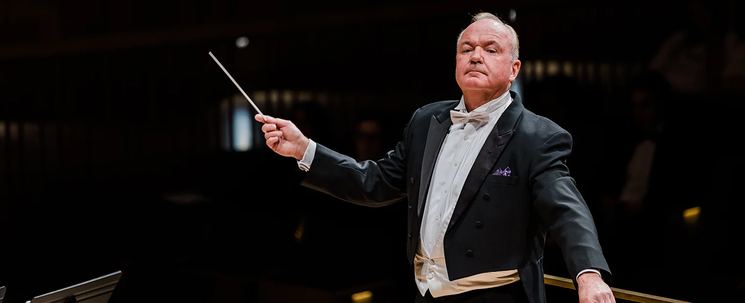 Bobby R. Francis, wearing a tuxedo, conducts the TCU Wind Symphony