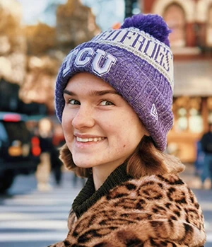 Caya wearing a leopard print coat and a TCU Horned Frogs beanie