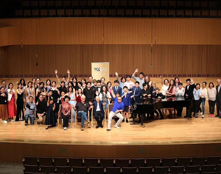 A large group of PianoTexas participants gather on the stage