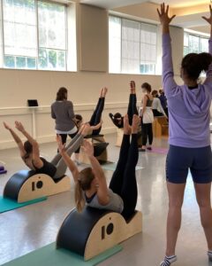 A room with people participating in a pilates class.