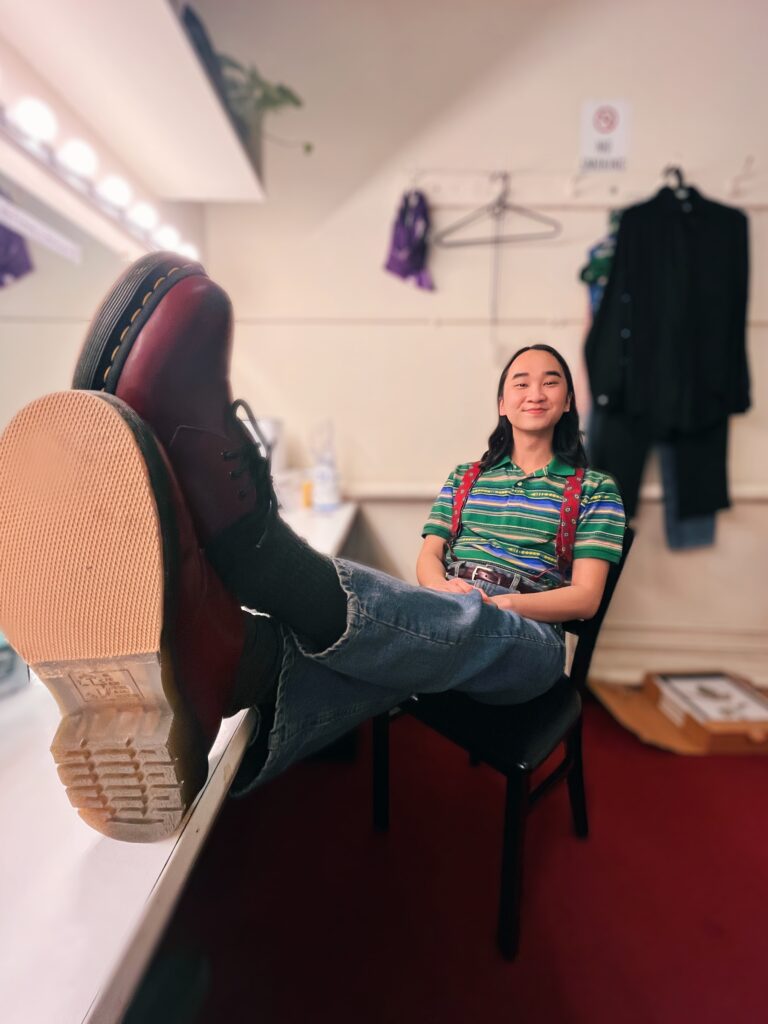 Vinh sitting in a chair in the “Kimberly Akimbo” dressing room.