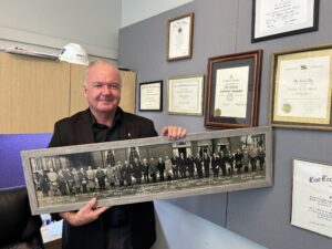 Francis proudly holds a photo from the inaugural convention held on March 13, 1930.