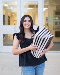 Avery Kokinda holds a collection of sketch books in front of the Fine Arts Building. 