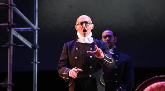 Corey Trahan performing on stage in a black suit.