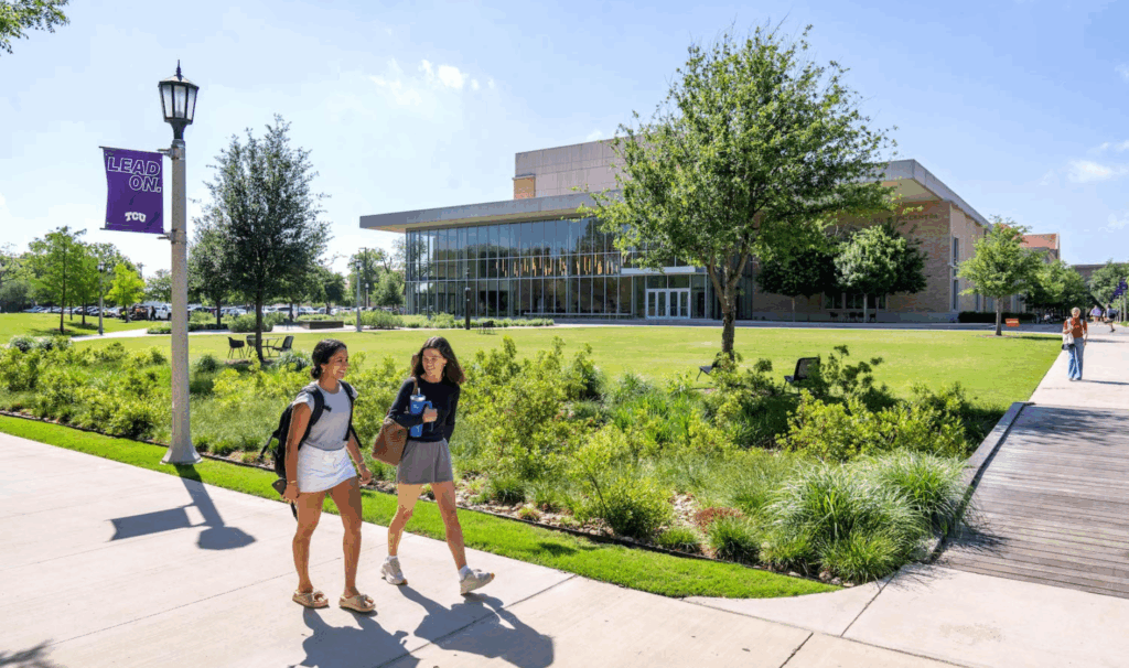 Two students walking through the Baker Martin Creative Commons with the Megan and Victor Boschini Music Center in the backdrop.